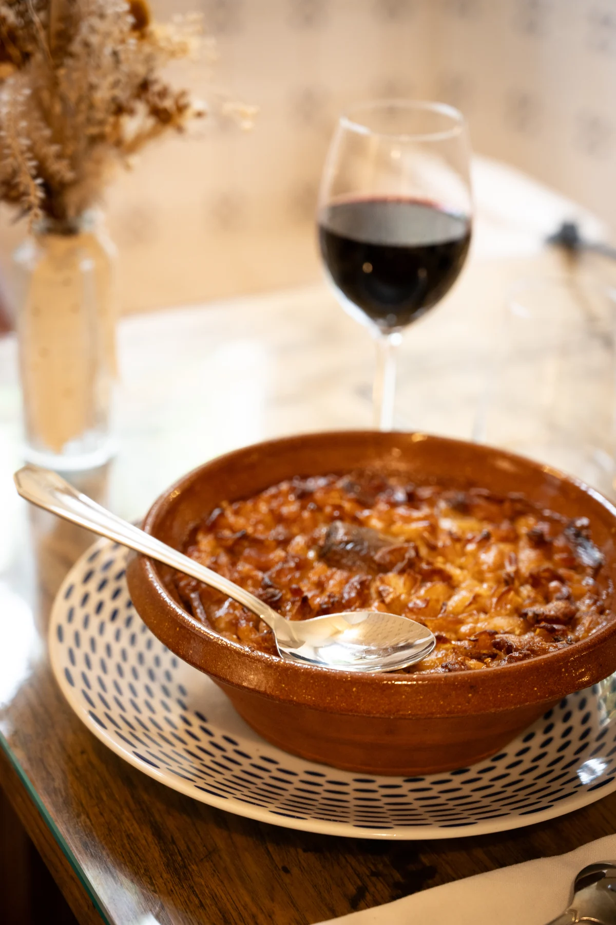 Cassoulet de Castelnaudary servi dans sa cassole en terre cuite, avec un verre de vin rouge, au restaurant du Domaine de Camboyer
