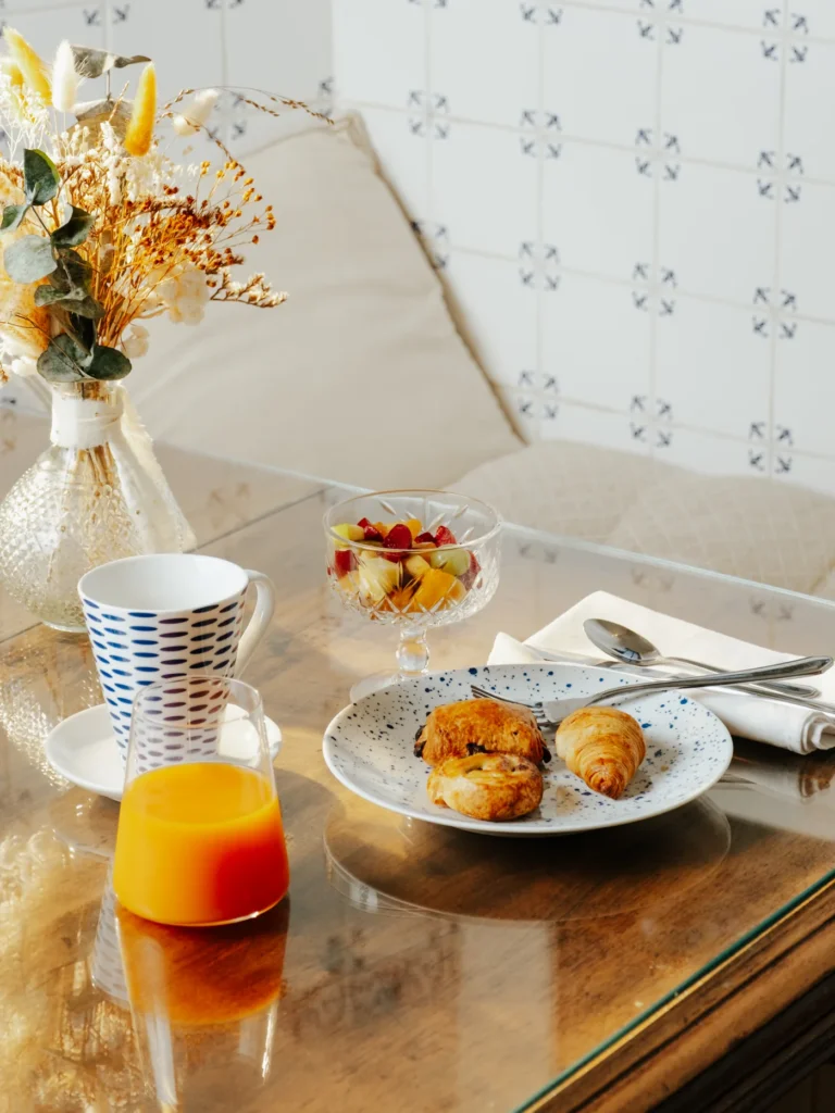 Plateau de petit-déjeuner avec viennoiseries, jus d'orange et fruits frais servi en chambre au Domaine de Camboyer